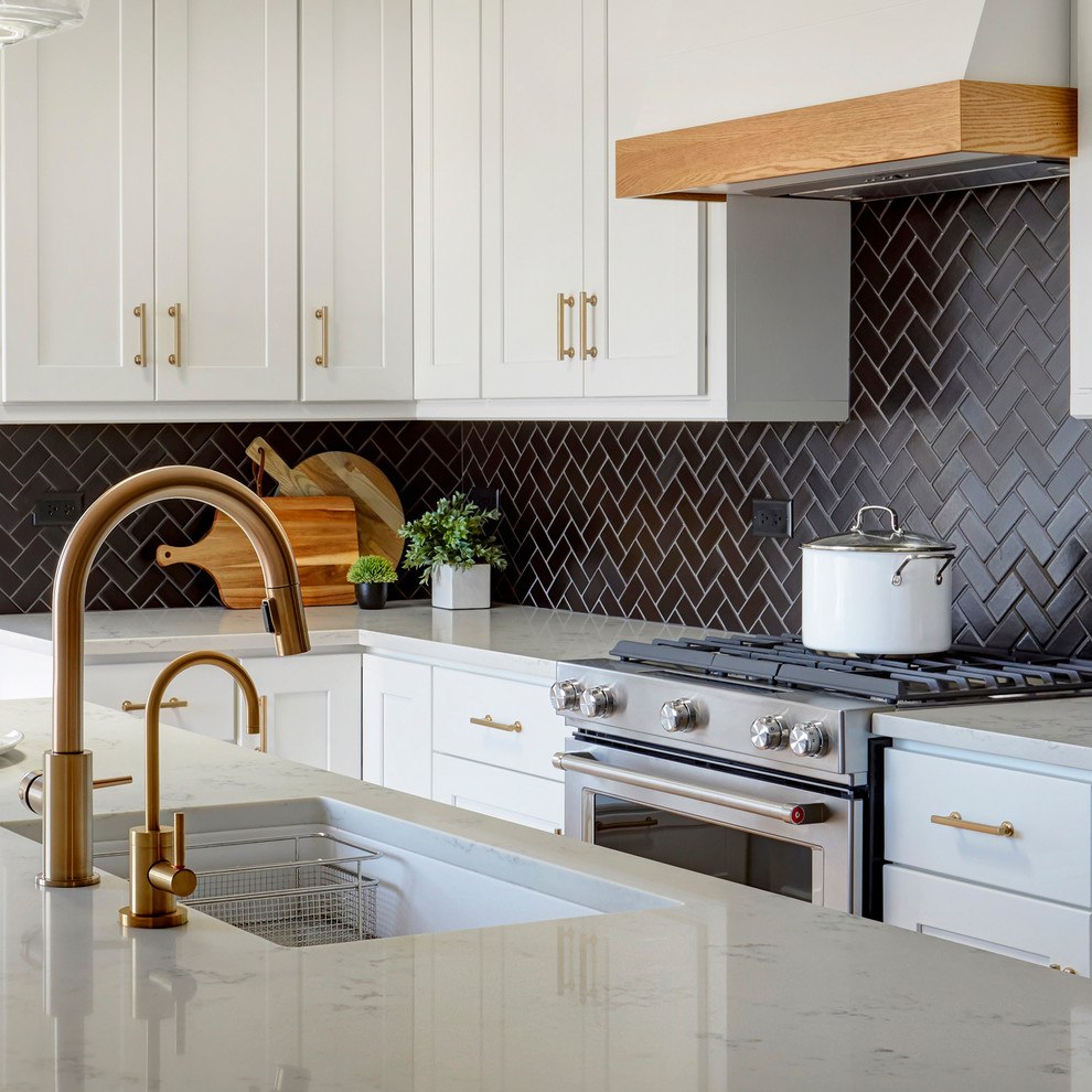 Eat-in kitchen - mid-sized coastal l-shaped medium tone wood floor and brown floor eat-in kitchen idea in Chicago with an undermount sink, shaker cabinets, white cabinets, quartz countertops, black backsplash, ceramic backsplash, stainless steel appliances, an island and white countertops