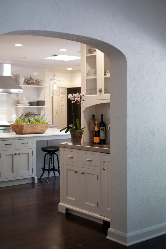 Exempel på ett modernt kök, med släta luckor, vita skåp, vitt stänkskydd, rostfria vitvaror, mörkt trägolv och en köksö
