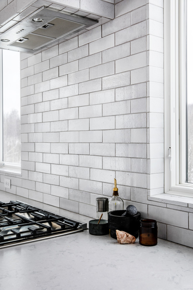 Exempel på ett stort nordiskt vit linjärt vitt kök och matrum, med en undermonterad diskho, släta luckor, grå skåp, bänkskiva i kvartsit, grått stänkskydd, stänkskydd i tegel, rostfria vitvaror, ljust trägolv, en köksö och beiget golv