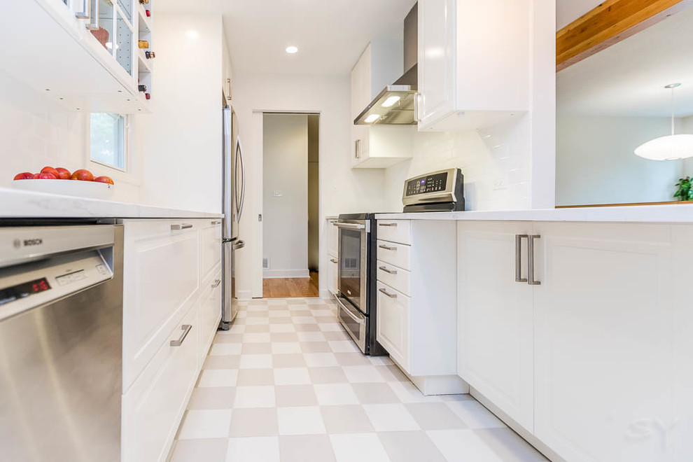 Photo of a small midcentury galley kitchen in Chicago with a single-bowl sink, shaker cabinets, white cabinets, engineered stone countertops, white splashback, metro tiled splashback, stainless steel appliances, ceramic flooring and grey floors.