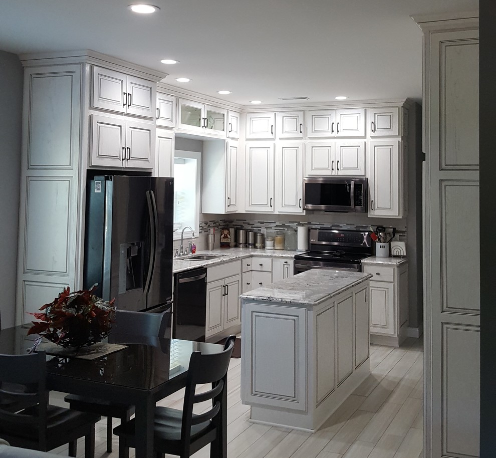 Inredning av ett klassiskt mellanstort kök, med en undermonterad diskho, luckor med upphöjd panel, vita skåp, granitbänkskiva, flerfärgad stänkskydd, stänkskydd i stickkakel, rostfria vitvaror, klinkergolv i porslin, en köksö och beiget golv