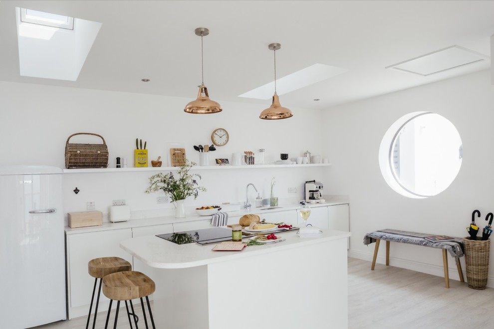 Inspiration for a scandi single-wall kitchen in Hampshire with a submerged sink, flat-panel cabinets, white cabinets, light hardwood flooring and an island.