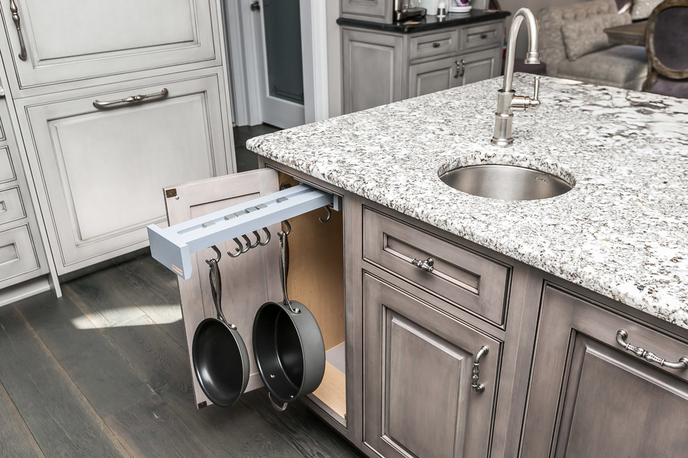 Example of a large classic u-shaped medium tone wood floor and gray floor eat-in kitchen design in Baltimore with a farmhouse sink, beaded inset cabinets, gray cabinets, granite countertops, gray backsplash, white appliances and an island