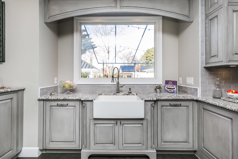 This is an example of a large traditional u-shaped kitchen/diner in Baltimore with a belfast sink, beaded cabinets, grey cabinets, granite worktops, grey splashback, white appliances, medium hardwood flooring, an island and grey floors.