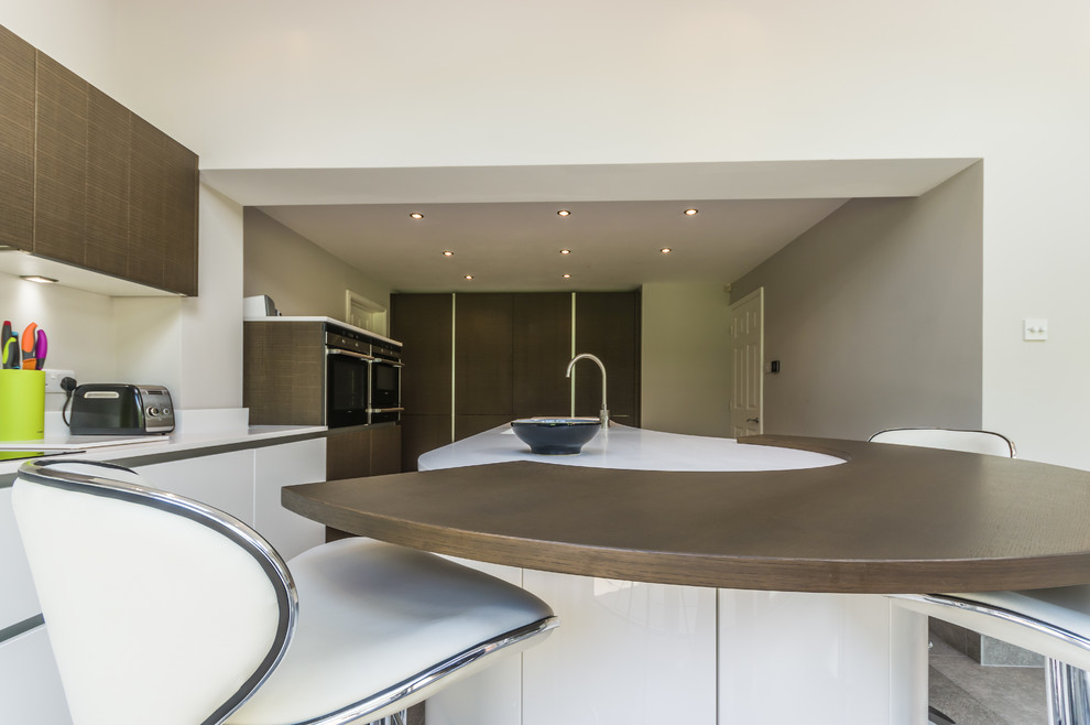 Large contemporary l-shaped open plan kitchen in Cheshire with a double-bowl sink, flat-panel cabinets, white cabinets, composite countertops, white splashback, stainless steel appliances, porcelain flooring and an island.