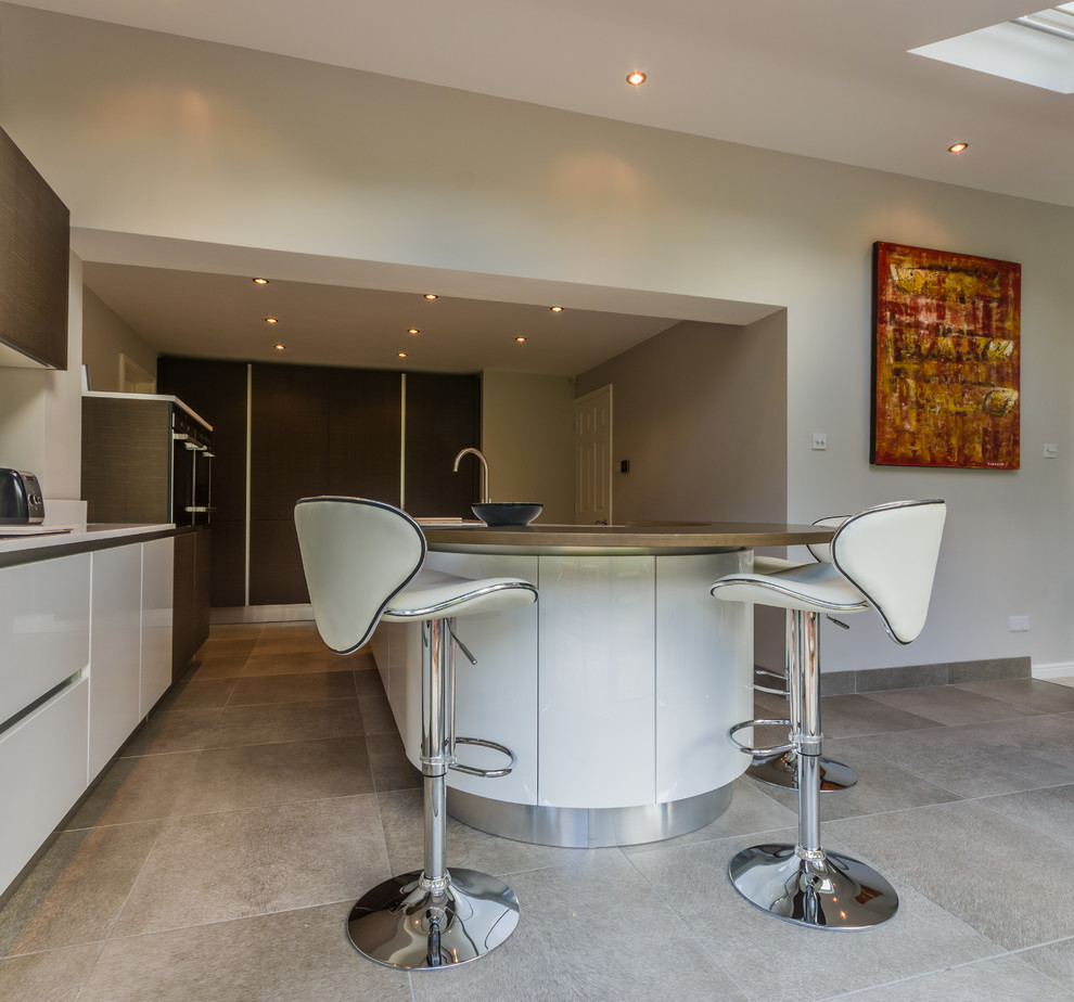 This is an example of a large contemporary l-shaped open plan kitchen in Cheshire with a double-bowl sink, flat-panel cabinets, white cabinets, composite countertops, stainless steel appliances, porcelain flooring and an island.