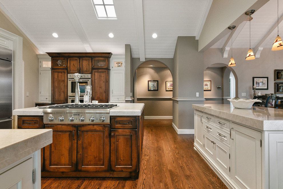 Large elegant u-shaped medium tone wood floor and brown floor open concept kitchen photo in San Francisco with a single-bowl sink, beaded inset cabinets, white cabinets, quartzite countertops, beige backsplash, subway tile backsplash, stainless steel appliances and an island