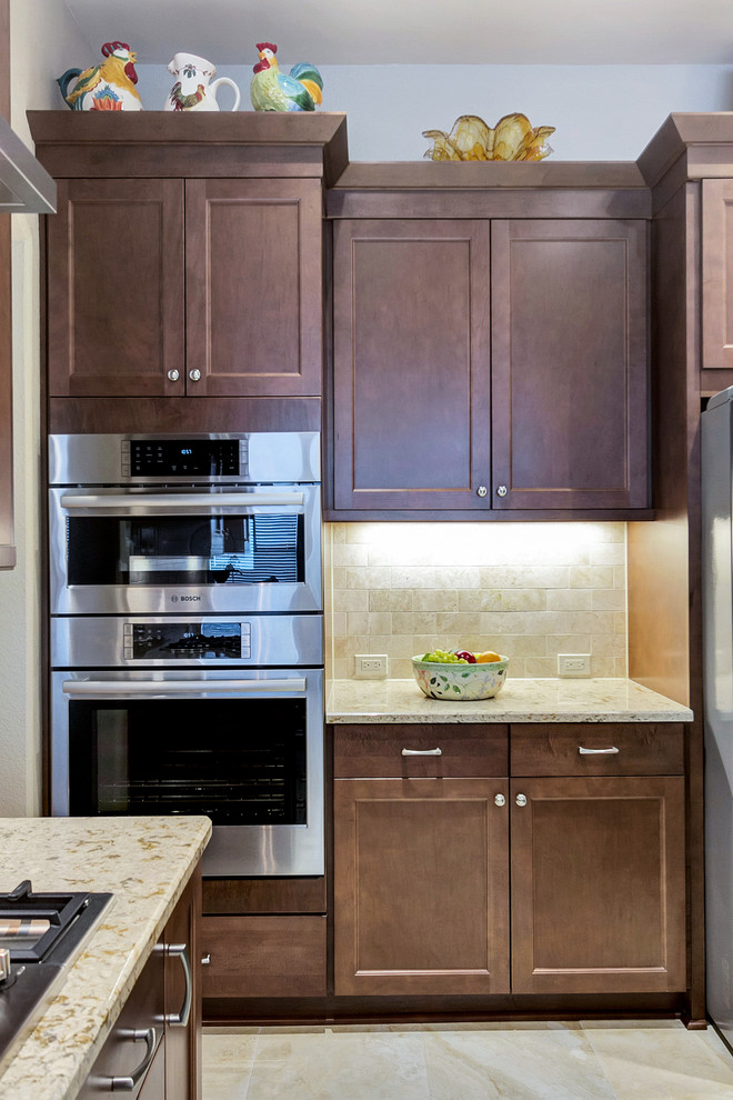 Exempel på ett mellanstort klassiskt kök, med en undermonterad diskho, luckor med infälld panel, skåp i mellenmörkt trä, bänkskiva i kvarts, beige stänkskydd, stänkskydd i stenkakel, rostfria vitvaror, travertin golv och en köksö