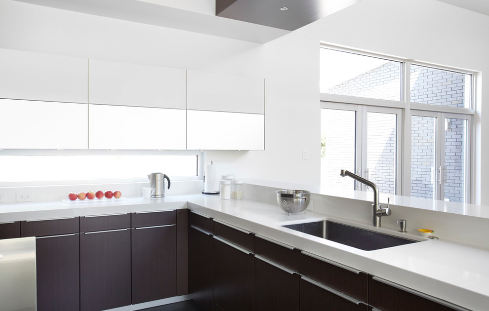 Стильный дизайн: кухня в стиле модернизм с врезной мойкой, плоскими фасадами, темными деревянными фасадами, белым фартуком и окном - последний тренд