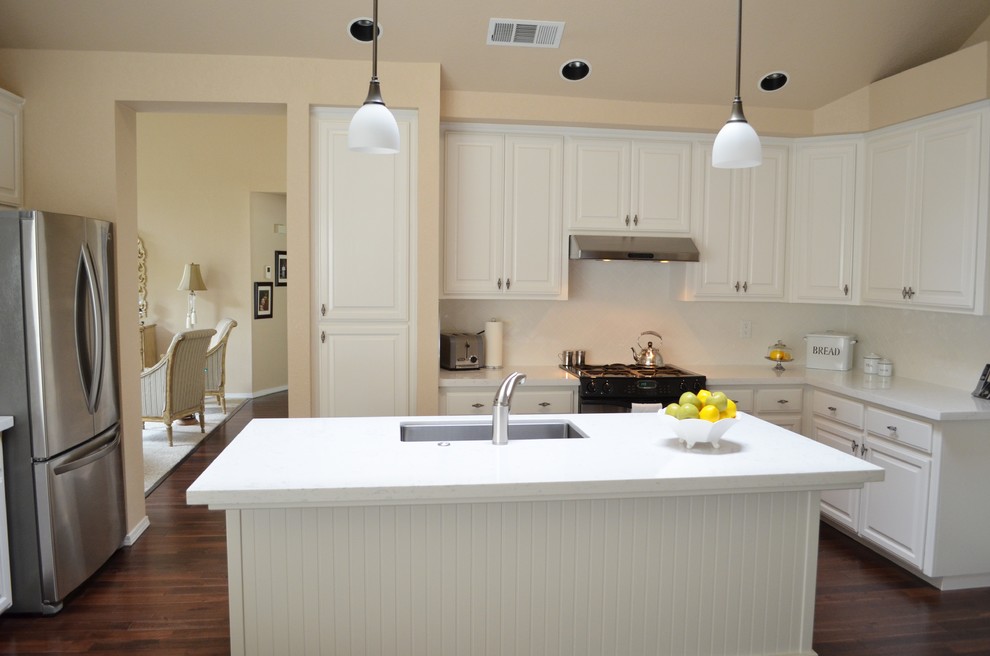 Inredning av ett modernt mellanstort kök, med en enkel diskho, luckor med upphöjd panel, vita skåp, bänkskiva i kvarts, vitt stänkskydd, stänkskydd i tunnelbanekakel, rostfria vitvaror, mörkt trägolv och en köksö
