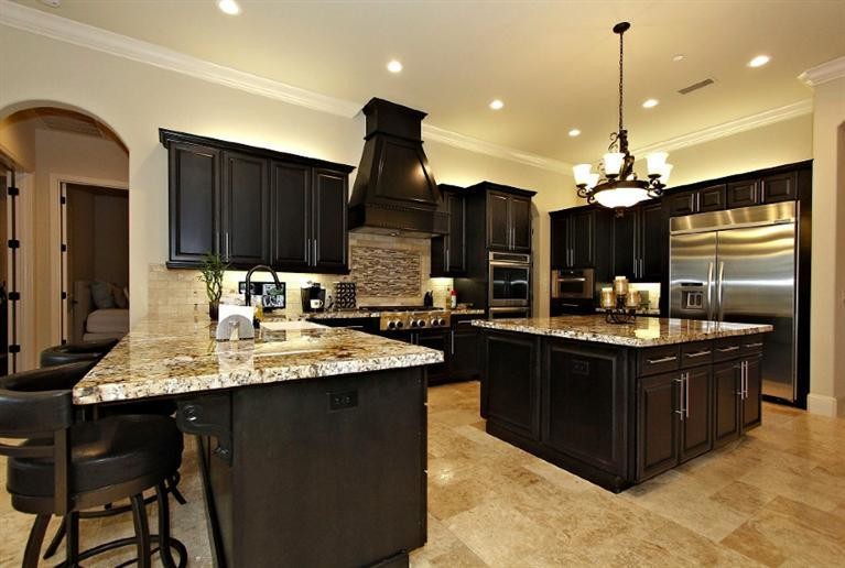 Example of a mid-sized tuscan u-shaped eat-in kitchen design in Other with a farmhouse sink, raised-panel cabinets, dark wood cabinets, granite countertops, beige backsplash, matchstick tile backsplash, stainless steel appliances and an island