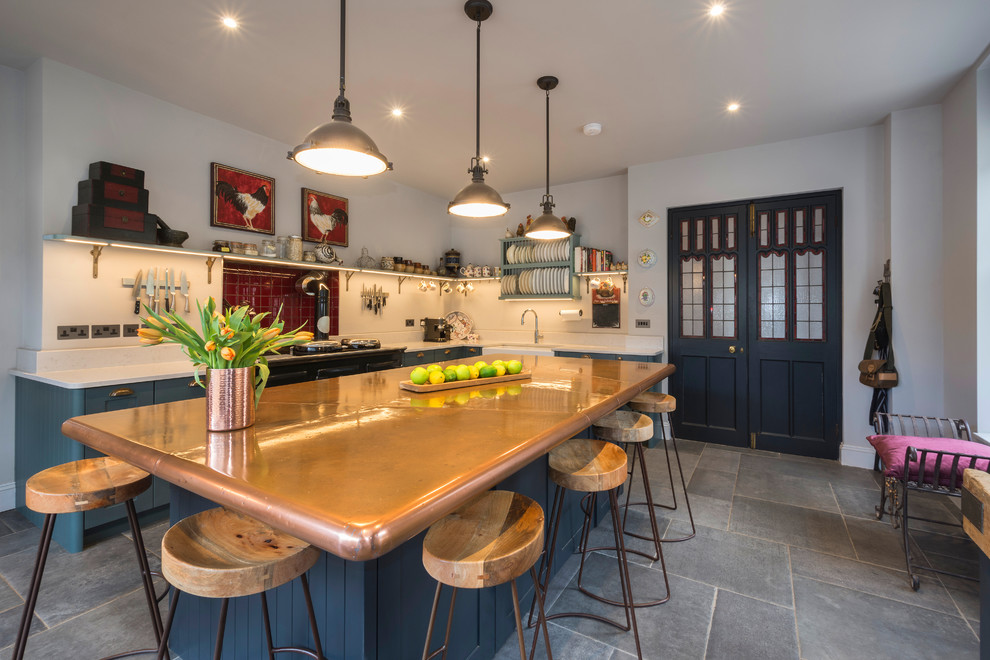 Klassische Küche in L-Form mit Landhausspüle, Schrankfronten im Shaker-Stil, blauen Schränken, Kupfer-Arbeitsplatte, bunten Elektrogeräten, Kücheninsel und grauem Boden in Cornwall
