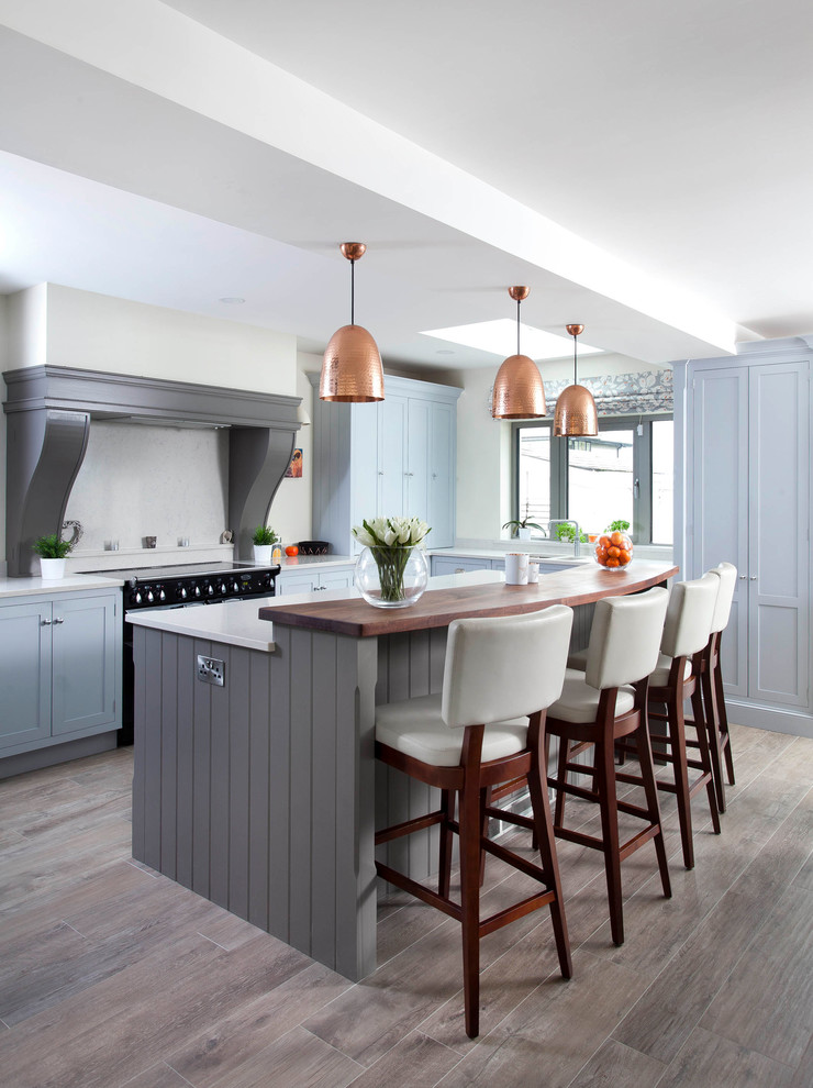 Inspiration for a large rural l-shaped kitchen/diner in Other with blue cabinets, wood worktops, medium hardwood flooring, an island, grey floors, brown worktops, a submerged sink, shaker cabinets, white splashback and black appliances.