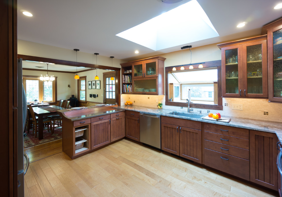 Exempel på ett klassiskt kök, med en undermonterad diskho, luckor med glaspanel, skåp i mellenmörkt trä, granitbänkskiva, beige stänkskydd, stänkskydd i stenkakel och rostfria vitvaror