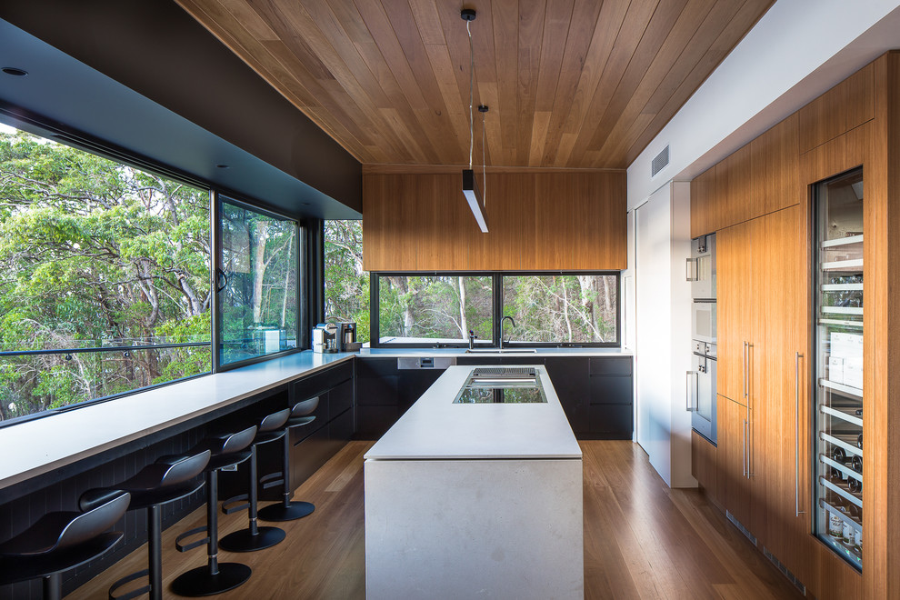Idées déco pour une cuisine moderne en U et bois brun avec un évier encastré, un placard à porte plane, fenêtre, un électroménager en acier inoxydable, un sol en bois brun et îlot.