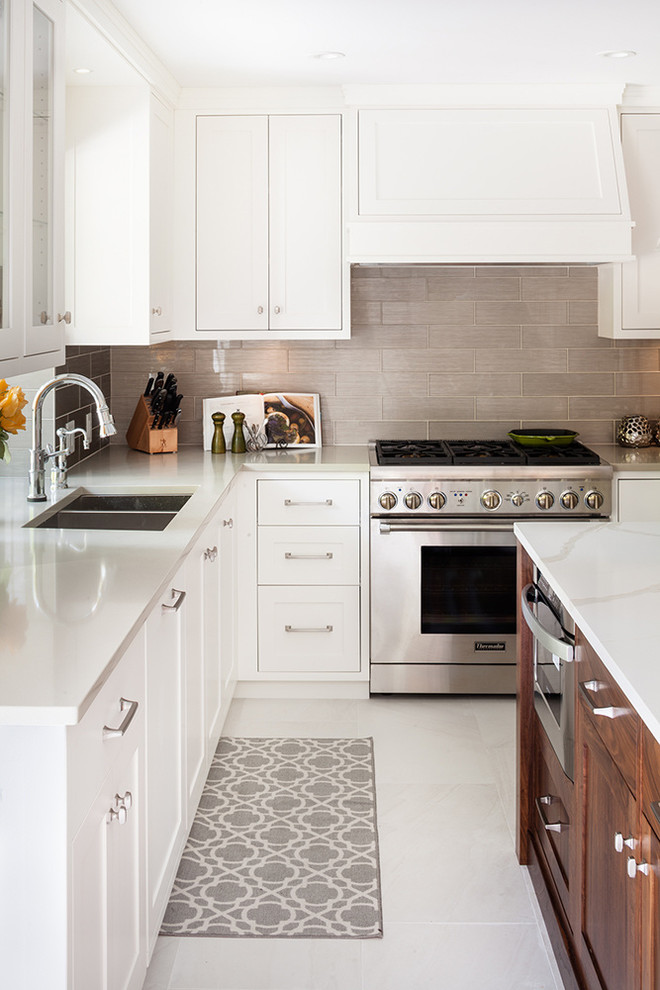 Kitchen - transitional l-shaped kitchen idea in Vancouver with an undermount sink, shaker cabinets, white cabinets, gray backsplash, stainless steel appliances and an island