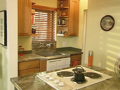 Exempel på ett litet exotiskt kök, med en enkel diskho, skåp i shakerstil, skåp i mellenmörkt trä, granitbänkskiva, grönt stänkskydd, stänkskydd i sten, vita vitvaror, marmorgolv och en köksö