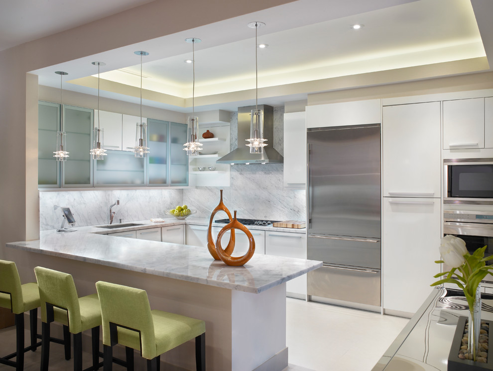 マイアミにある高級な中くらいなコンテンポラリースタイルのおしゃれなキッチン (フラットパネル扉のキャビネット、白いキャビネット、白いキッチンパネル、シルバーの調理設備) の写真