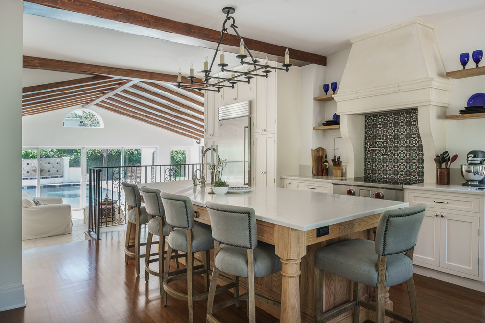 Example of a tuscan dark wood floor kitchen design in Miami with shaker cabinets, beige cabinets, multicolored backsplash, cement tile backsplash, stainless steel appliances and an island
