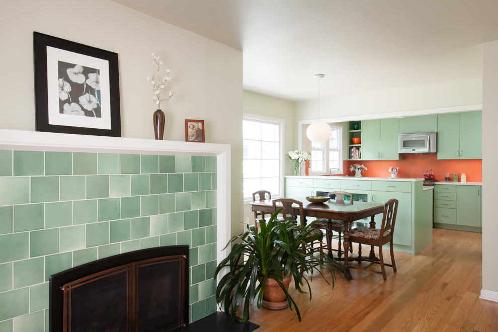 Inspiration for a small classic u-shaped kitchen/diner in Portland with a submerged sink, flat-panel cabinets, green cabinets, orange splashback, ceramic splashback, stainless steel appliances and light hardwood flooring.