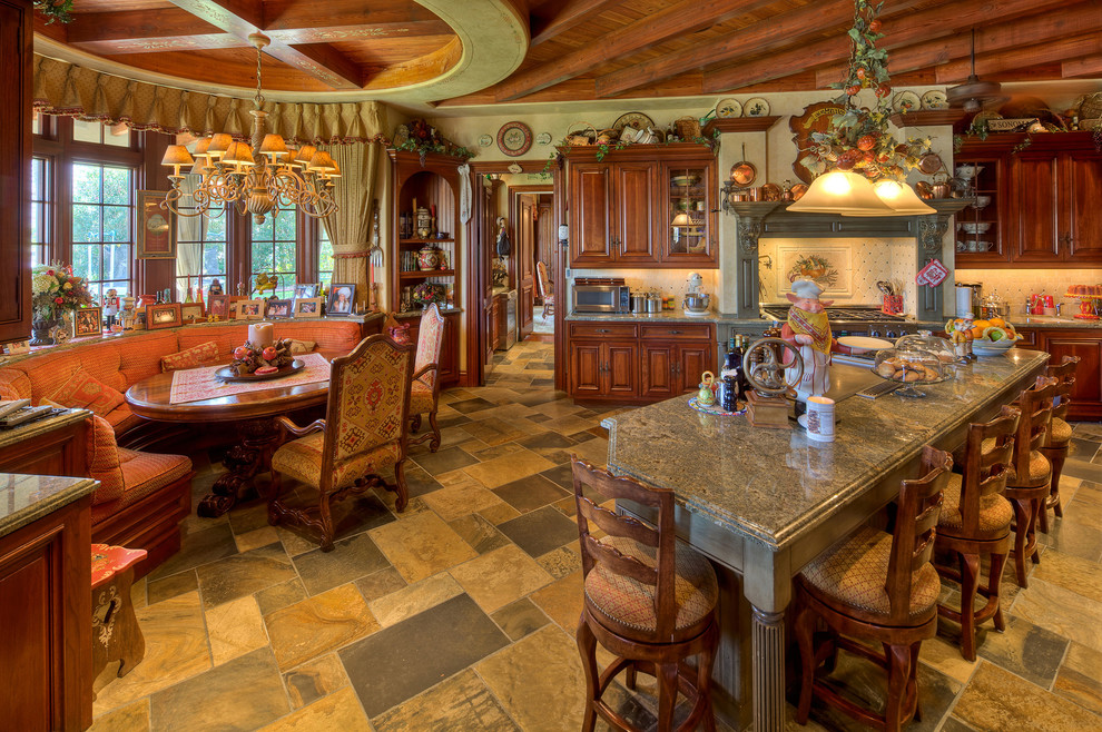 Пример оригинального дизайна: кухня в средиземноморском стиле с обеденным столом, фасадами с выступающей филенкой, темными деревянными фасадами, полом из керамической плитки и островом