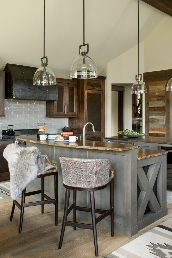 Rustikale Küchenbar mit dunklen Holzschränken, Küchenrückwand in Grau, Rückwand aus Metrofliesen, hellem Holzboden und Kücheninsel in Sonstige