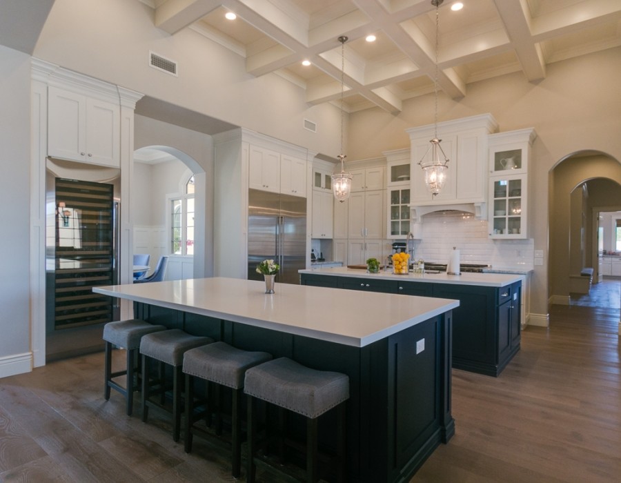 Inspiration for a large transitional l-shaped dark wood floor and brown floor open concept kitchen remodel in Phoenix with an undermount sink, shaker cabinets, white cabinets, quartz countertops, white backsplash, subway tile backsplash, stainless steel appliances and two islands