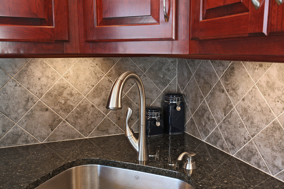 Exempel på ett mellanstort retro kök, med en enkel diskho, luckor med upphöjd panel, röda skåp, granitbänkskiva, grått stänkskydd, stänkskydd i keramik, svarta vitvaror och klinkergolv i keramik