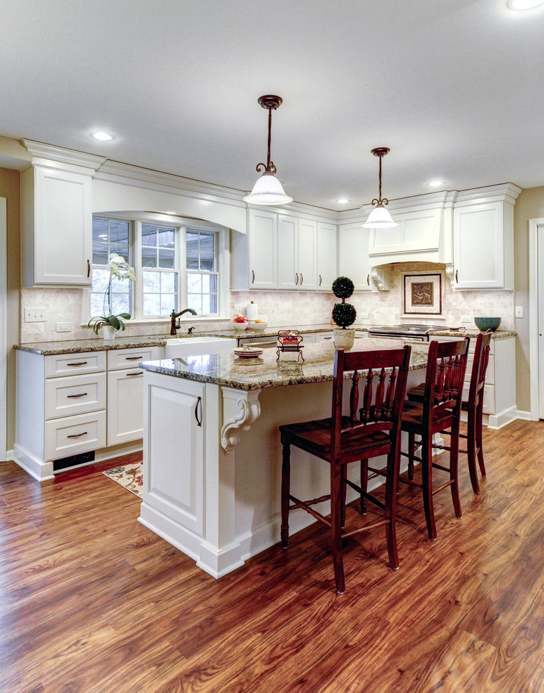 Inspiration for a transitional u-shaped cork floor and brown floor eat-in kitchen remodel in Philadelphia with a farmhouse sink, white cabinets, granite countertops, white backsplash, travertine backsplash, stainless steel appliances and an island