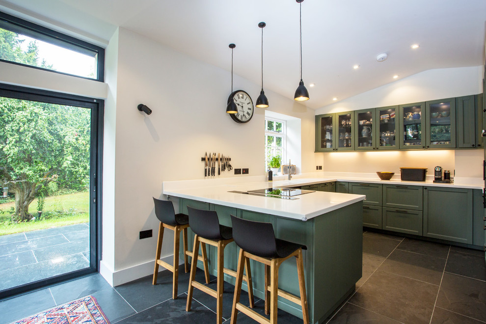 Inspiration for a traditional u-shaped kitchen in West Midlands with glass-front cabinets, green cabinets, no island and composite countertops.