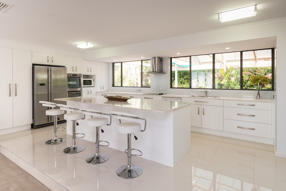 Example of a large trendy porcelain tile eat-in kitchen design in Other with an undermount sink, white cabinets, white backsplash, glass sheet backsplash, stainless steel appliances, an island and solid surface countertops