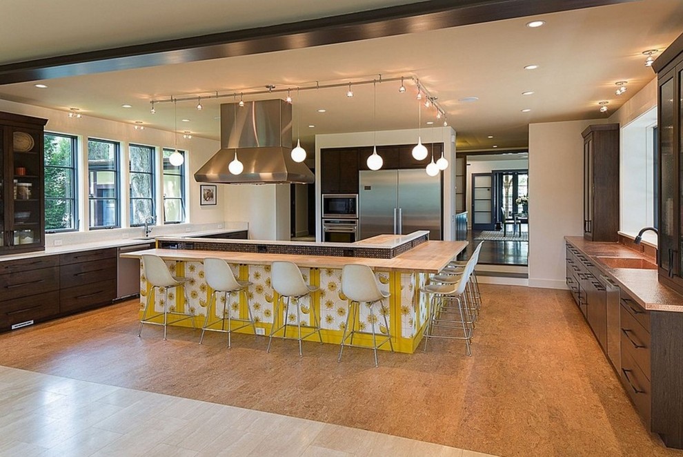 Large transitional u-shaped cork floor eat-in kitchen photo in New York with an integrated sink, glass-front cabinets, dark wood cabinets, wood countertops, stainless steel appliances and an island