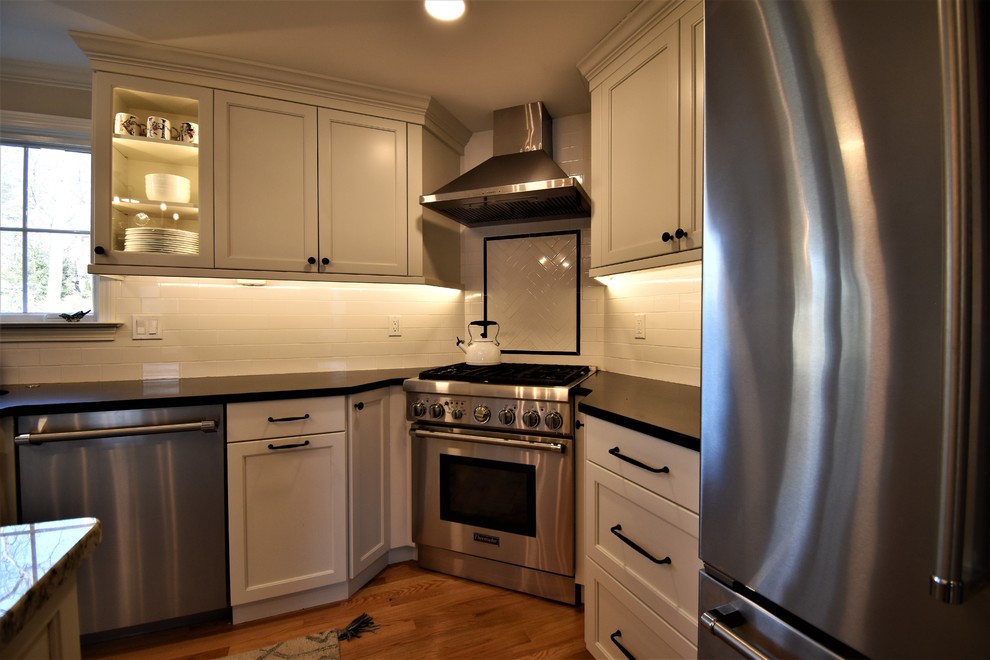 Küche in L-Form mit Schrankfronten mit vertiefter Füllung, weißen Schränken und Kücheninsel in Sonstige