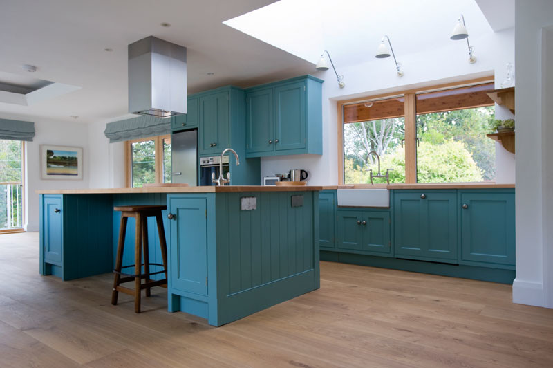 Große Maritime Wohnküche mit Unterbauwaschbecken, blauen Schränken, Arbeitsplatte aus Holz, Küchengeräten aus Edelstahl, braunem Holzboden und Kücheninsel in Cornwall
