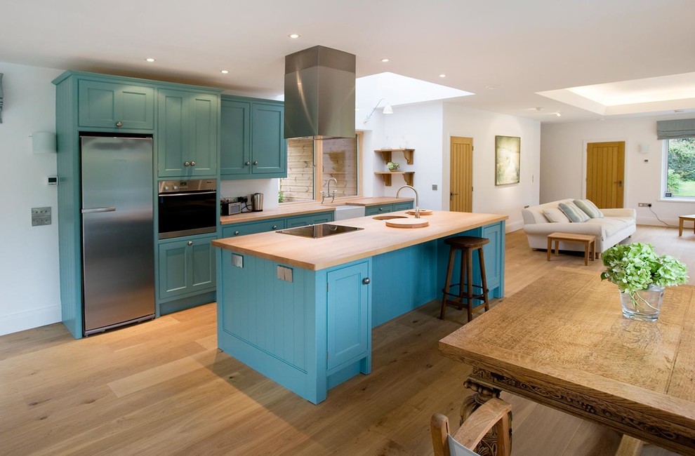 Large beach style kitchen/diner in Cornwall with a submerged sink, blue cabinets, wood worktops, stainless steel appliances, medium hardwood flooring and an island.