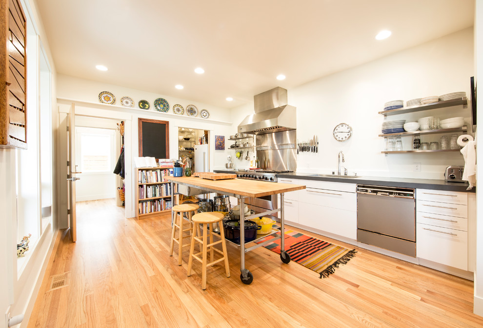 Moderne Küche in L-Form mit Unterbauwaschbecken, flächenbündigen Schrankfronten, weißen Schränken, Küchenrückwand in Gelb, Küchengeräten aus Edelstahl, braunem Holzboden, Kücheninsel, braunem Boden und grauer Arbeitsplatte in Seattle