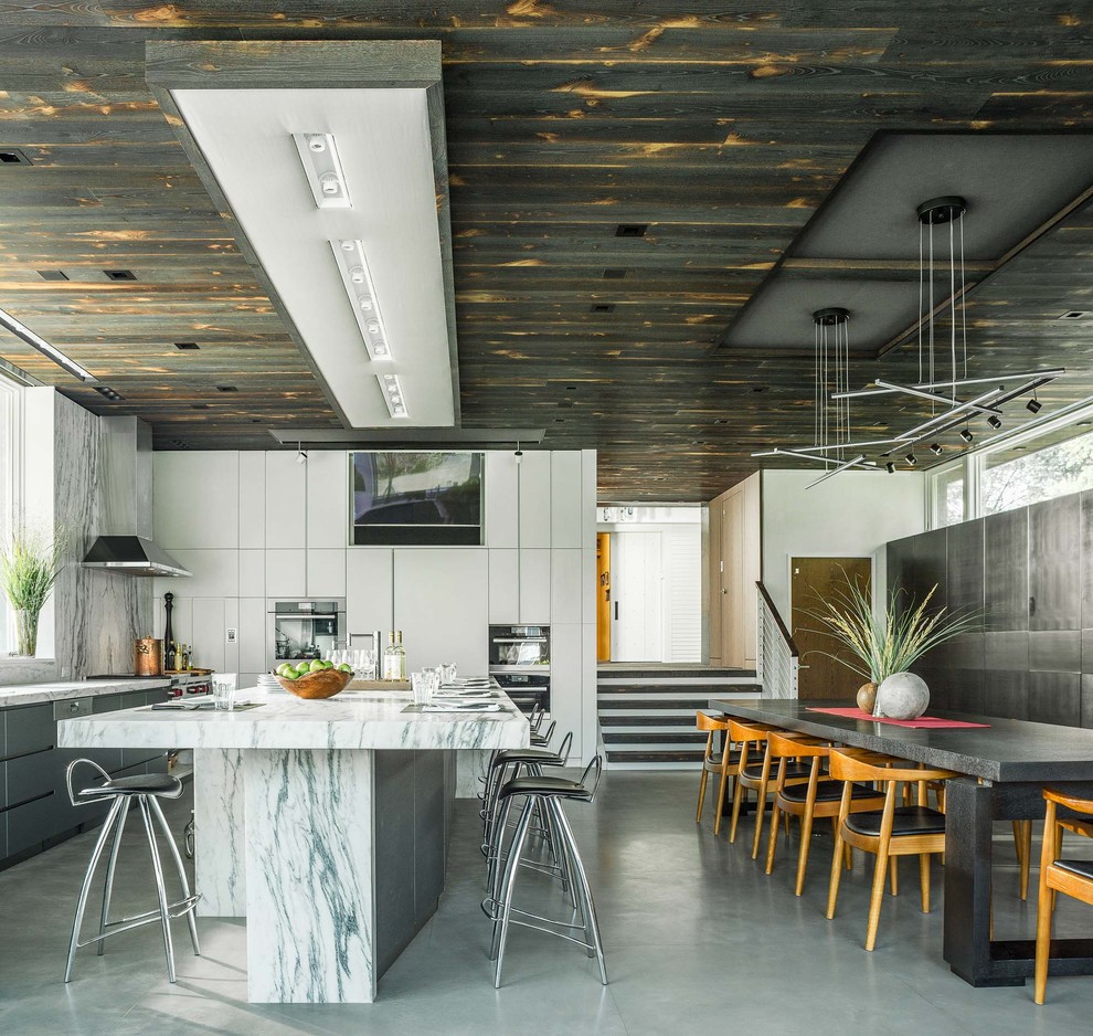 Foto på ett funkis kök, med släta luckor, vita skåp, rostfria vitvaror, en köksö och grått golv