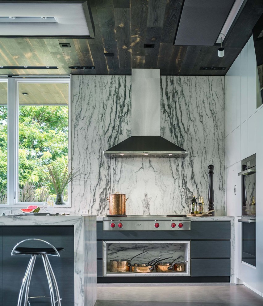 Esempio di una cucina design con ante lisce, ante blu, paraspruzzi in lastra di pietra, elettrodomestici in acciaio inossidabile e pavimento grigio