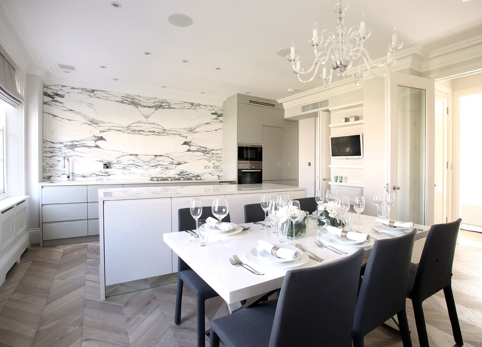 Contemporary kitchen/diner in London with a submerged sink, flat-panel cabinets, multi-coloured splashback, stainless steel appliances, light hardwood flooring and an island.