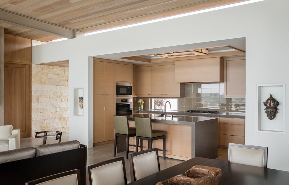 Offene Moderne Küche mit flächenbündigen Schrankfronten, hellen Holzschränken, Küchenrückwand in Grau, Küchengeräten aus Edelstahl und Rückwand aus Glasfliesen in Orange County
