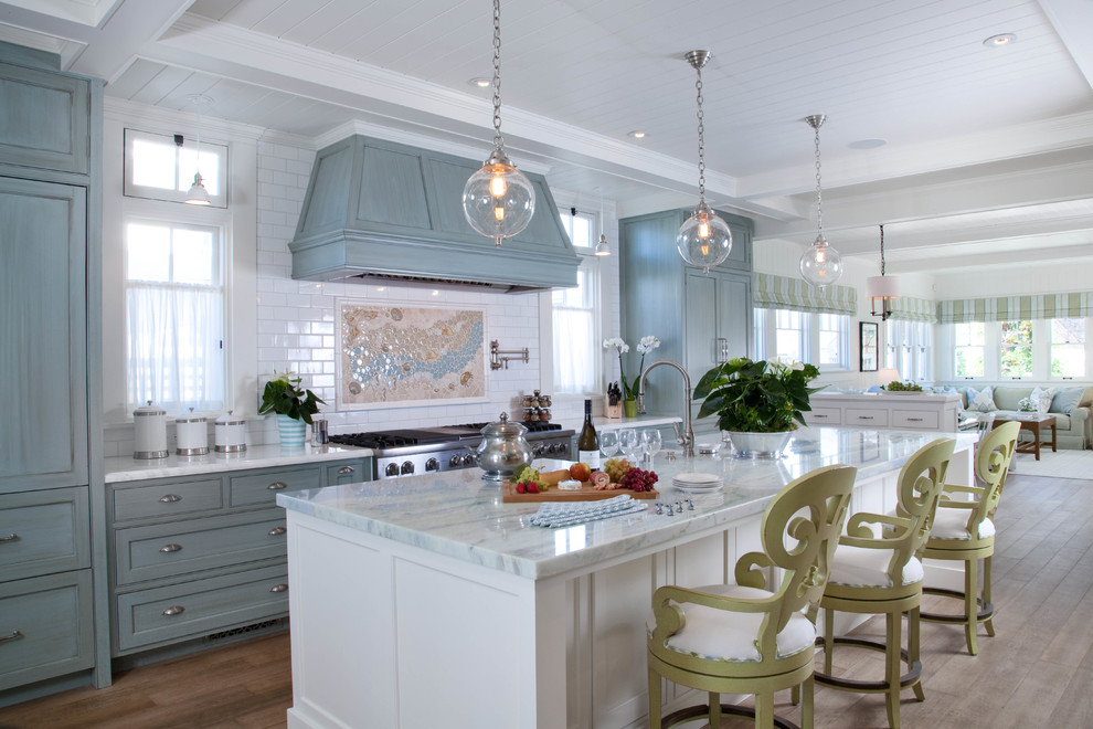 Bild på ett maritimt kök, med skåp i shakerstil, marmorbänkskiva, vitt stänkskydd, stänkskydd i tunnelbanekakel, rostfria vitvaror, en köksö, en rustik diskho, mellanmörkt trägolv och blå skåp
