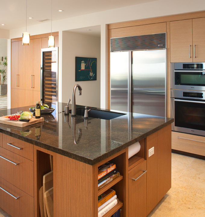 This is an example of a large modern l-shaped kitchen/diner in San Diego with flat-panel cabinets, granite worktops, stainless steel appliances, an island, a submerged sink, medium wood cabinets, blue splashback, glass sheet splashback, travertine flooring, beige floors and black worktops.
