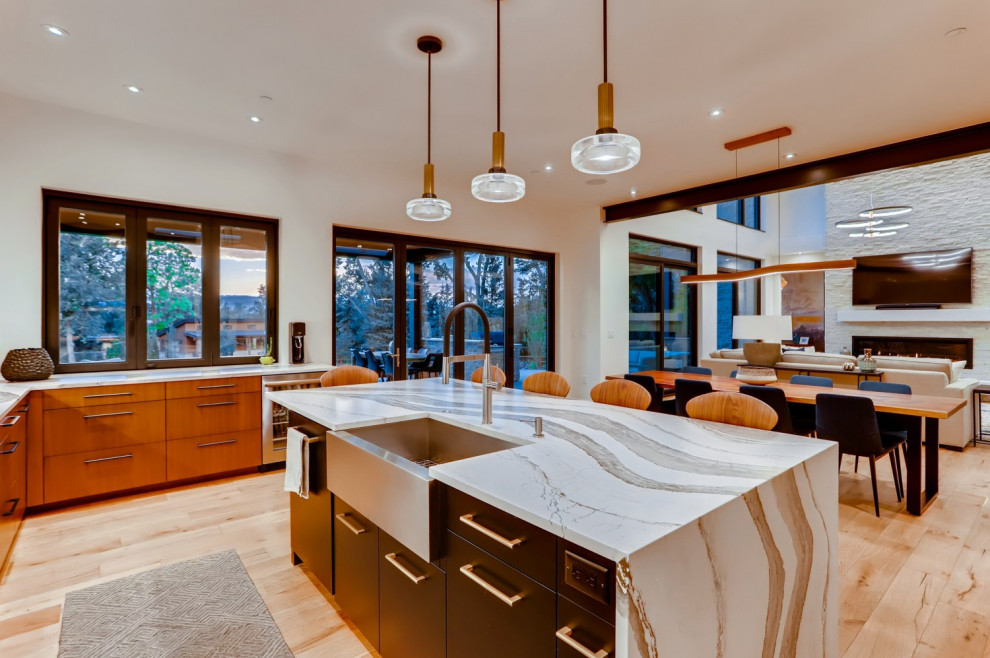Kitchen - large modern u-shaped light wood floor and brown floor kitchen idea in Denver with a farmhouse sink, flat-panel cabinets, medium tone wood cabinets, white backsplash, stainless steel appliances, an island and white countertops