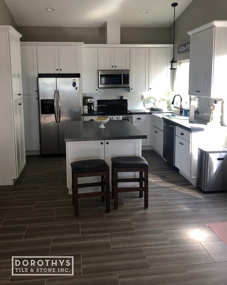 Modern inredning av ett stort kök, med en rustik diskho, skåp i shakerstil, vita skåp, bänkskiva i kvarts, vitt stänkskydd, stänkskydd i keramik, klinkergolv i porslin, en köksö och brunt golv