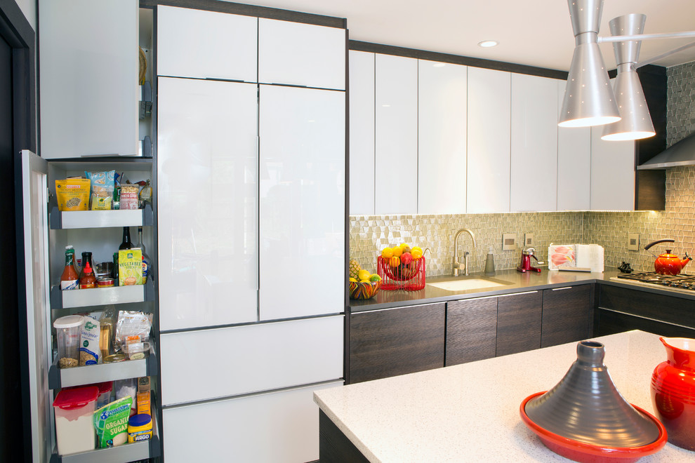 Foto på ett avskilt, litet funkis l-kök, med en undermonterad diskho, luckor med glaspanel, bänkskiva i kvarts, stänkskydd i glaskakel, rostfria vitvaror och en köksö