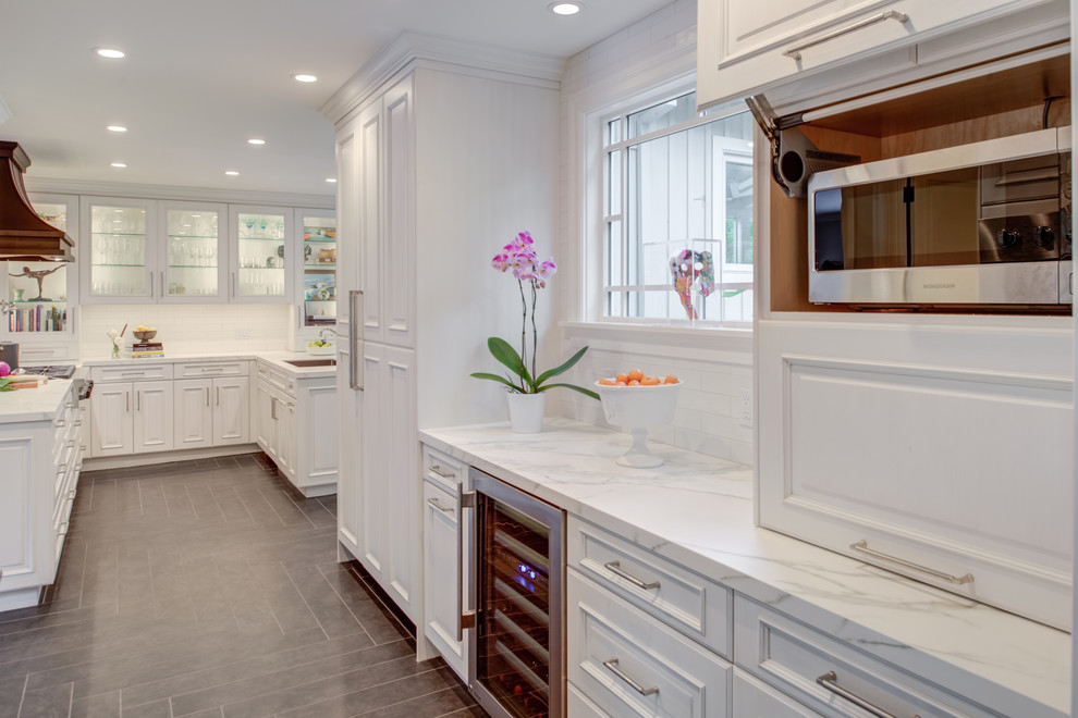 Photo of a classic u-shaped kitchen in San Francisco with a submerged sink, raised-panel cabinets, white cabinets, engineered stone countertops, white splashback, metro tiled splashback, integrated appliances, grey floors, white worktops and ceramic flooring.