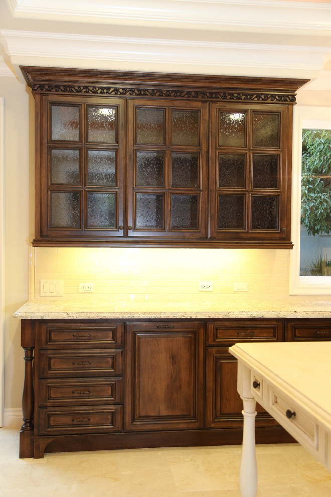 Inredning av ett medelhavsstil kök, med luckor med upphöjd panel, skåp i slitet trä, marmorbänkskiva och integrerade vitvaror
