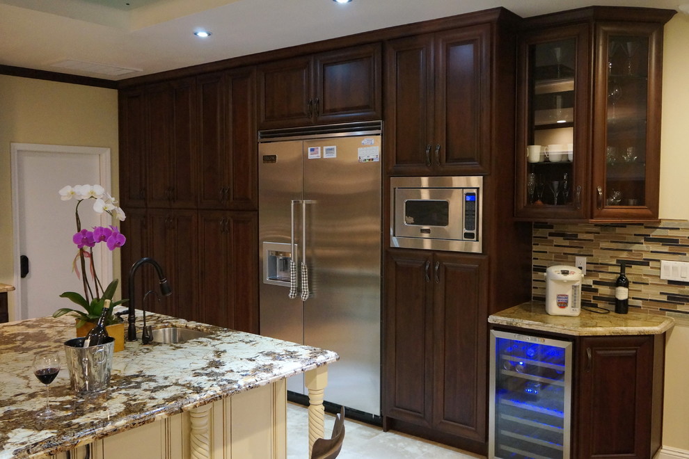 Photo of a large traditional u-shaped kitchen in Los Angeles with a double-bowl sink, raised-panel cabinets, dark wood cabinets, granite worktops, brown splashback, glass tiled splashback, stainless steel appliances, ceramic flooring, an island and multi-coloured floors.
