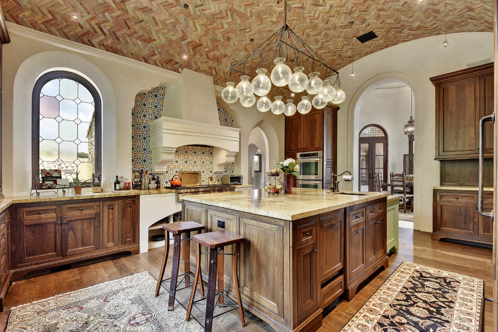 Inspiration for a mediterranean u-shaped dark wood floor kitchen remodel in Austin with recessed-panel cabinets, dark wood cabinets, multicolored backsplash and an island
