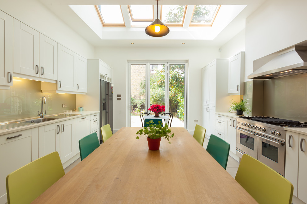 Idee per una cucina contemporanea di medie dimensioni con ante beige, paraspruzzi con lastra di vetro, elettrodomestici in acciaio inossidabile e pavimento beige